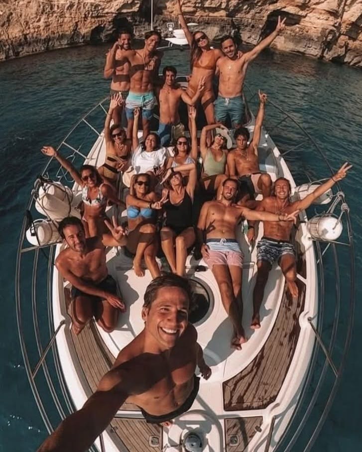 A group of guests celebrating aboard a chartered yacht anchored in a rocky cove
