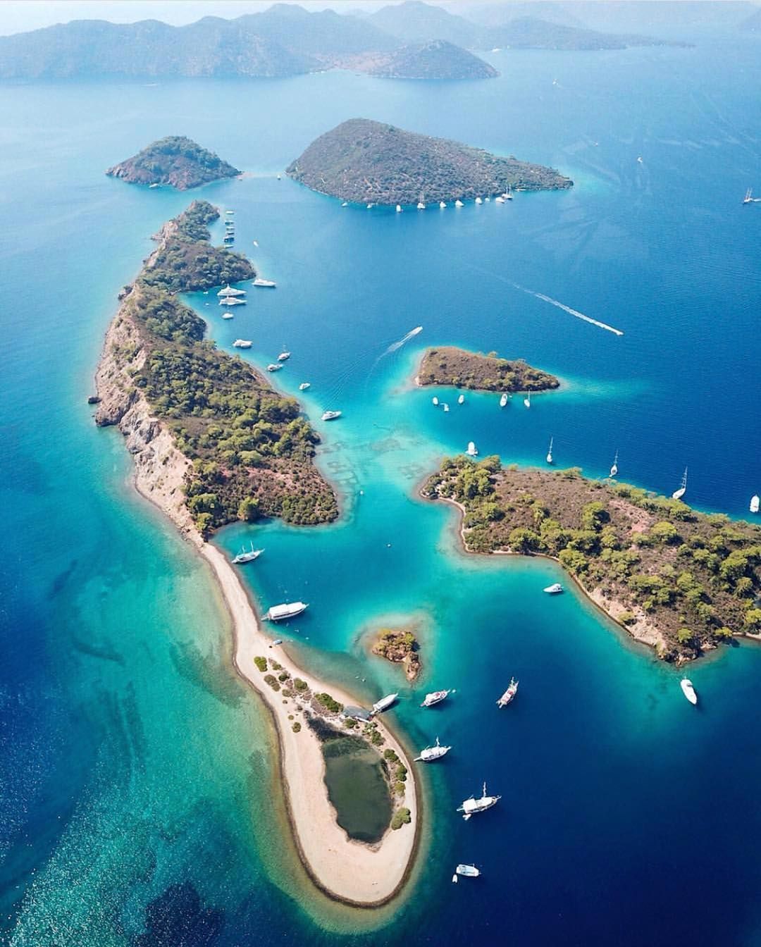 Aerial view of pine-covered islands and anchored gulets on the Turquoise Coast