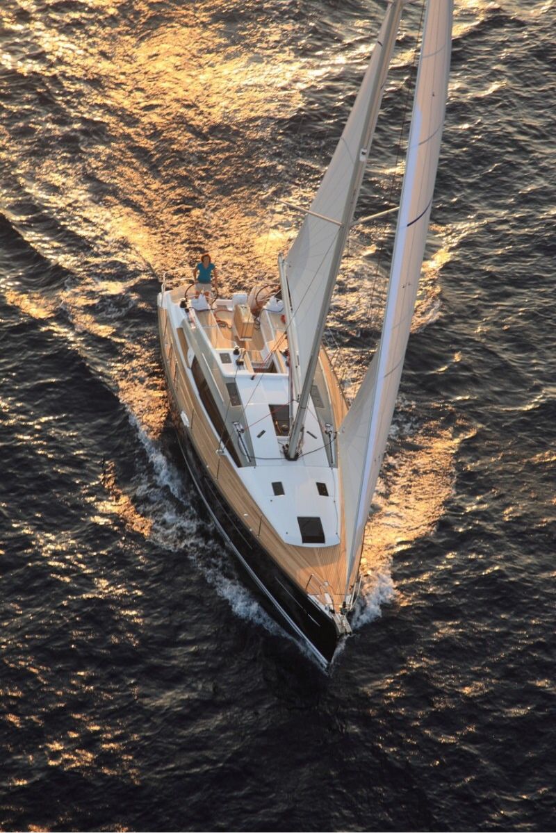 A sailing yacht cutting through golden evening water